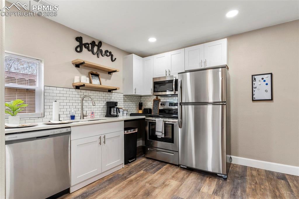 Image 37 of 43: Kitchen featuring stainless steel appliances, a sink, backsplash, light woo