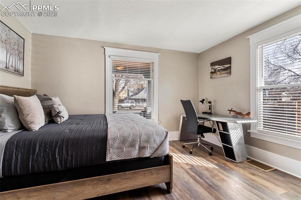 Image 6 of 43: Bedroom featuring wood finished floors, multiple windows, an office area, b