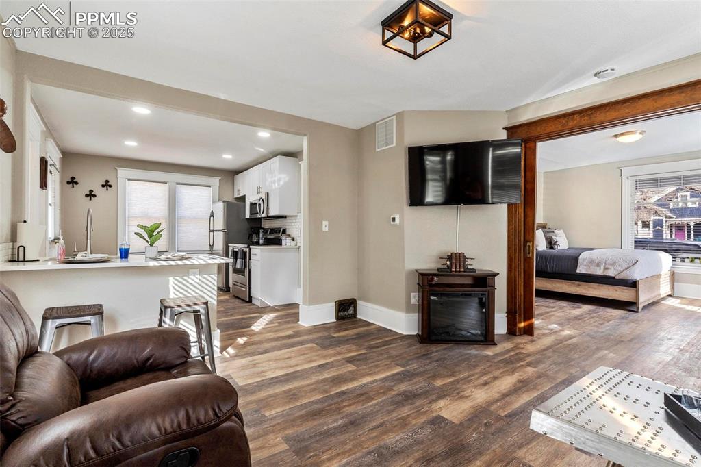 Image 8 of 43: Living area with dark wood-type flooring, baseboards, and recessed lighting
