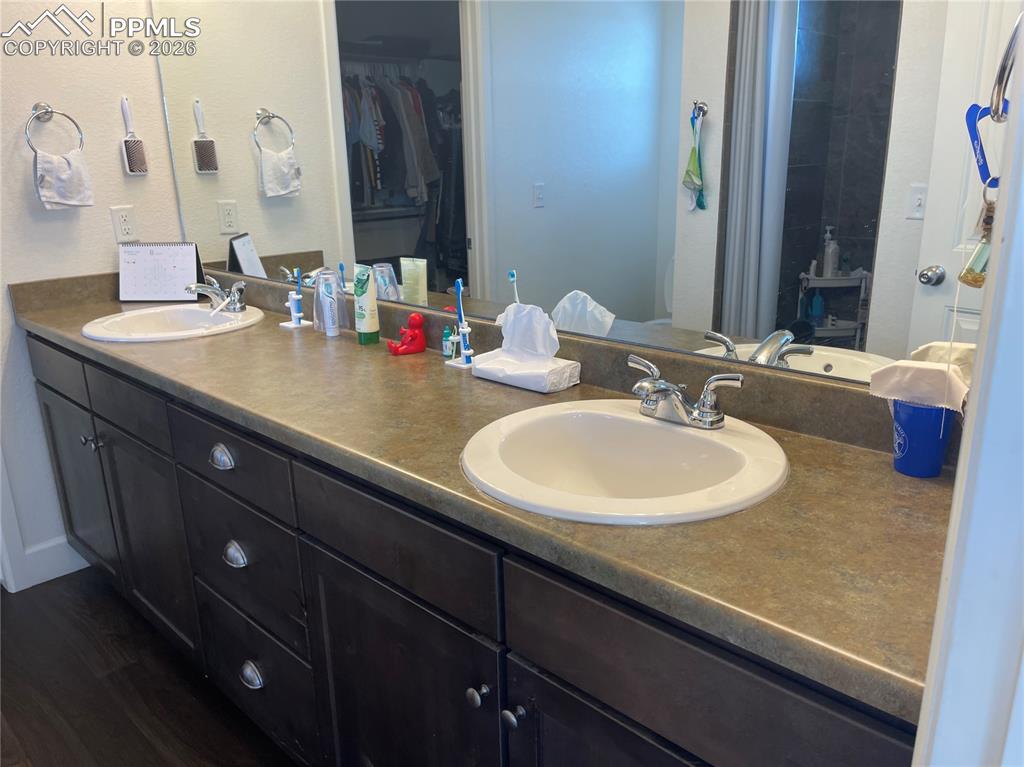 Image 12 of 25: Full bathroom featuring double vanity, dark wood-style flooring, and a walk