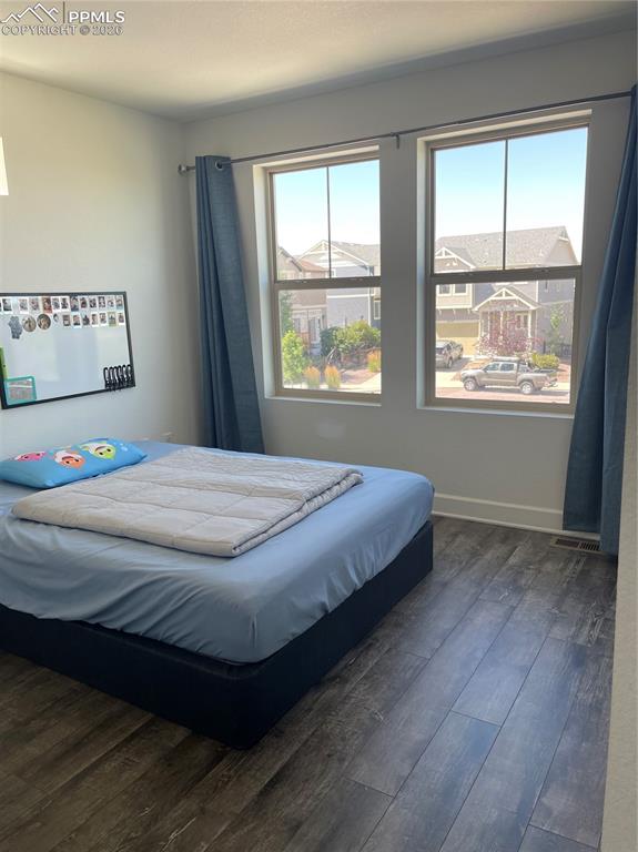 Image 16 of 25: Bedroom featuring dark wood-style floors and baseboards