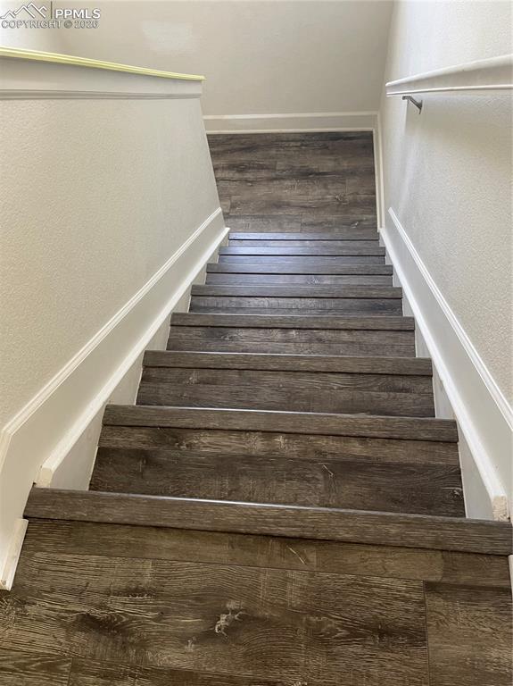 Image 17 of 25: Stairs featuring a textured wall and wood finished floors