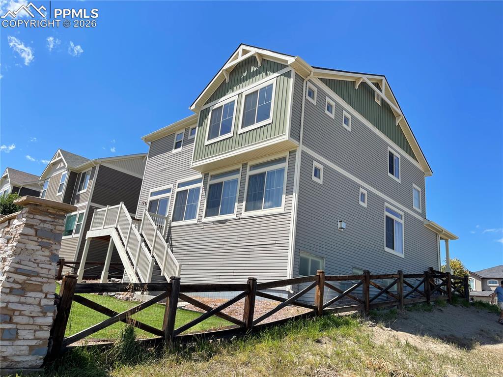 Image 23 of 25: Back of property featuring stairway and board and batten siding