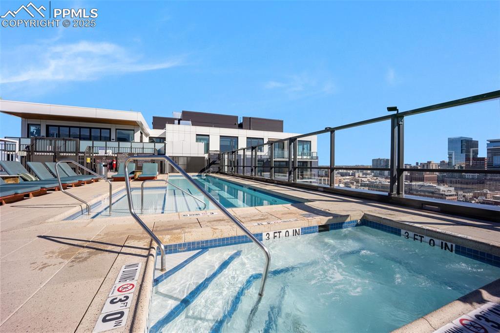 Image 10 of 50: View of pool with a pool, a hot tub, and a city view