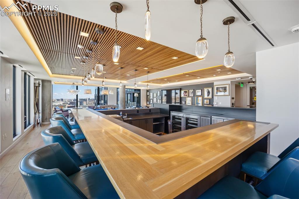 Image 12 of 50: Community bar area featuring wooden ceiling, wooden counters, pendant light