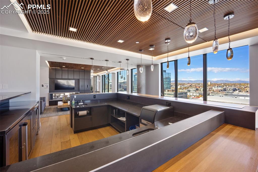 Image 13 of 50: Owners lounge bar and kitchen featuring decorative light fixtures, modern c