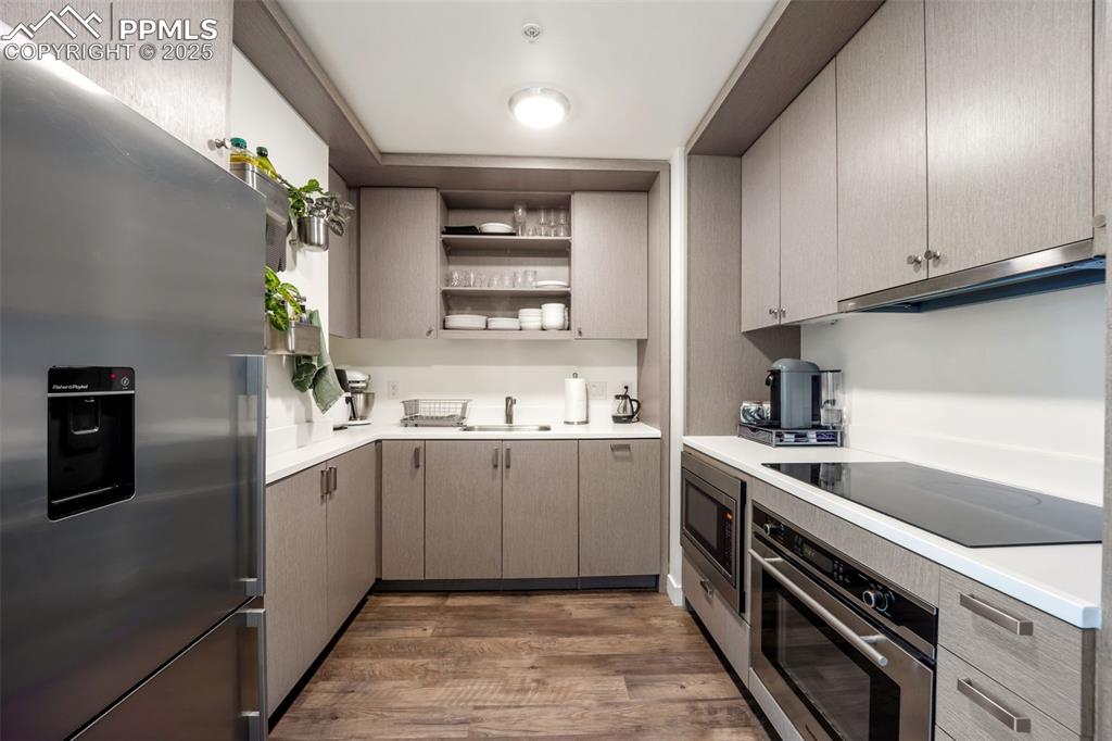 Image 26 of 50: Kitchen featuring stainless steel appliances, open shelves, light counterto