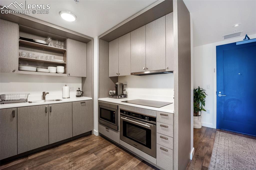 Image 27 of 50: Kitchen with open shelves, appliances with stainless steel finishes, light