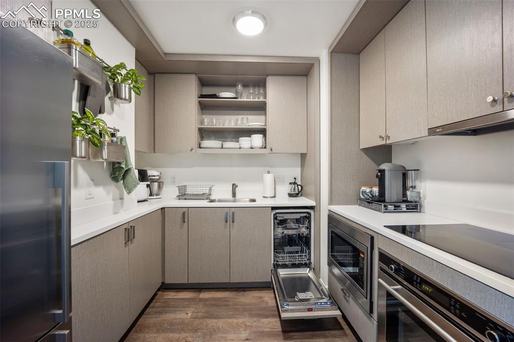 Image 29 of 50: Kitchen with appliances with stainless steel finishes, light countertops, d