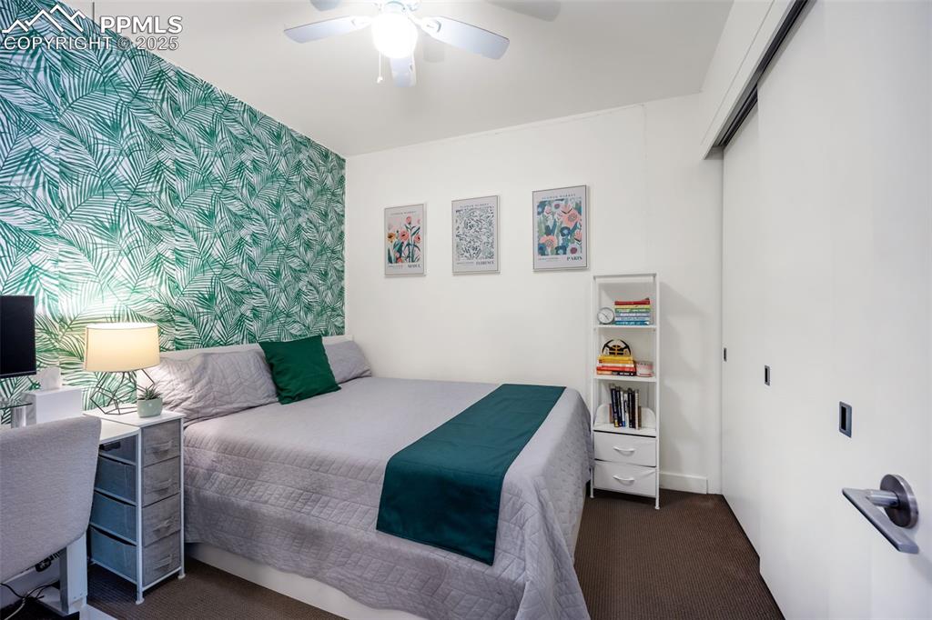 Image 30 of 50: Bedroom featuring a closet, wallpapered walls, dark colored carpet, an acce