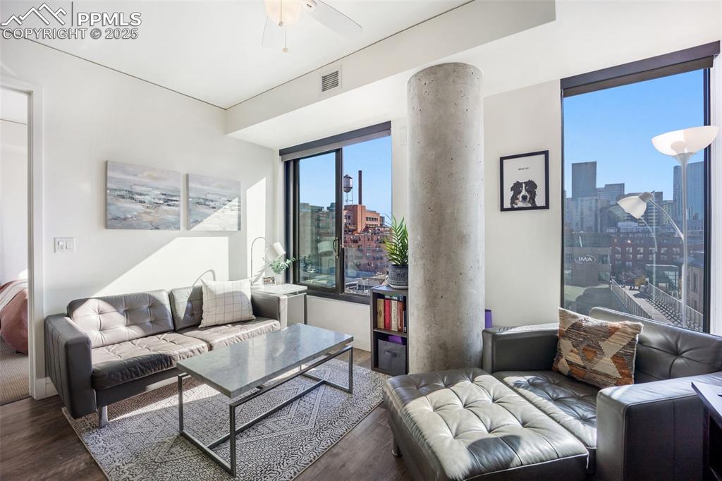 Image 35 of 50: Living room with wood finished floors, a city view, and a ceiling fan