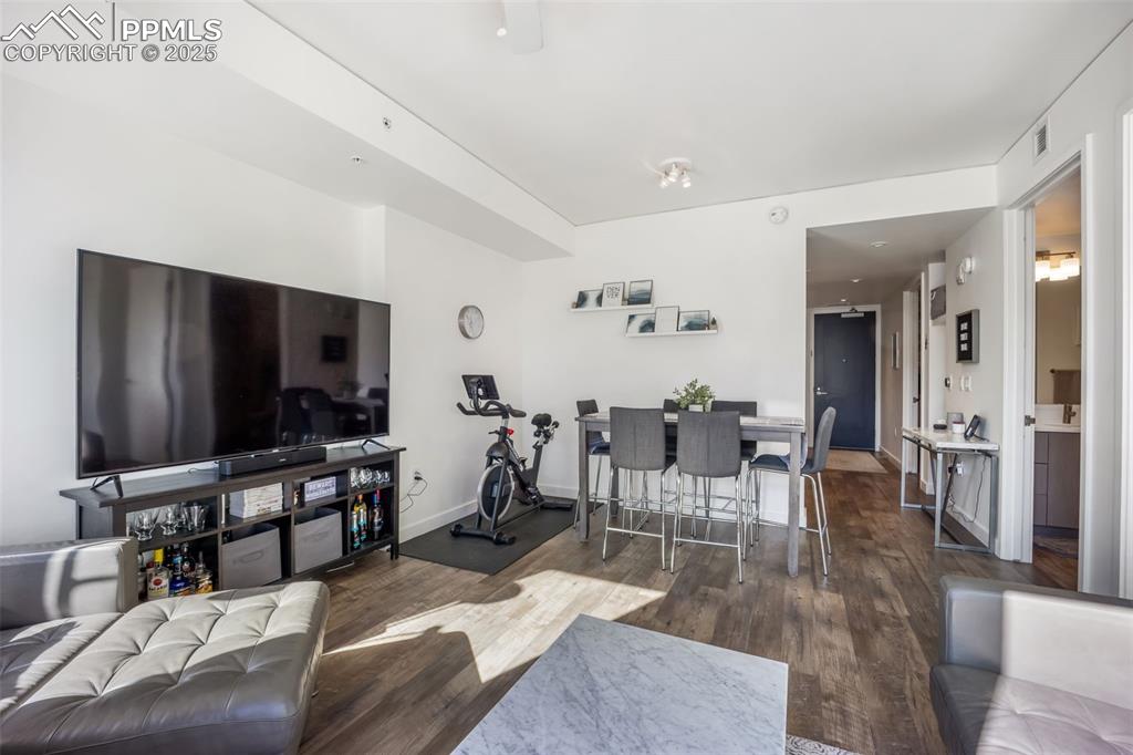 Image 36 of 50: Living area featuring dark wood-style flooring and baseboards
