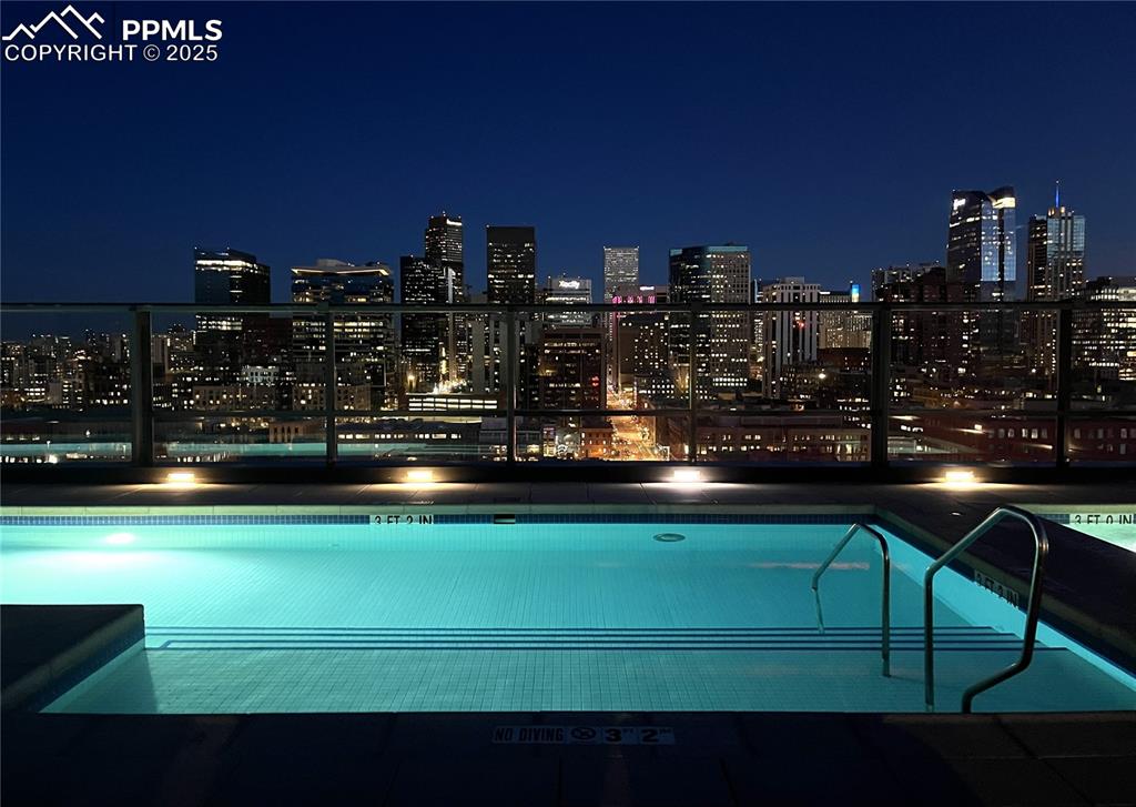 Image 47 of 50: Pool at twilight with a community pool, a patio, and a view of city lights
