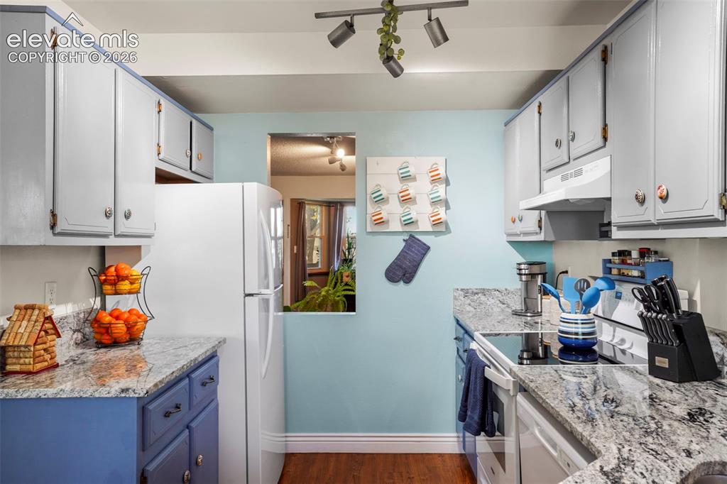 Image 11 of 28: Kitchen featuring natural stone countertops, custom cabinetry, wood-finish 