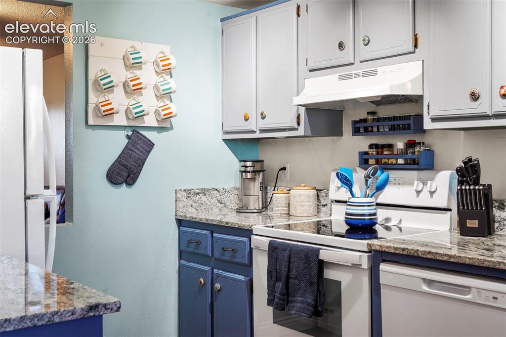 Image 13 of 28: Kitchen featuring stone countertops, two-toned cabinetry, an electric range