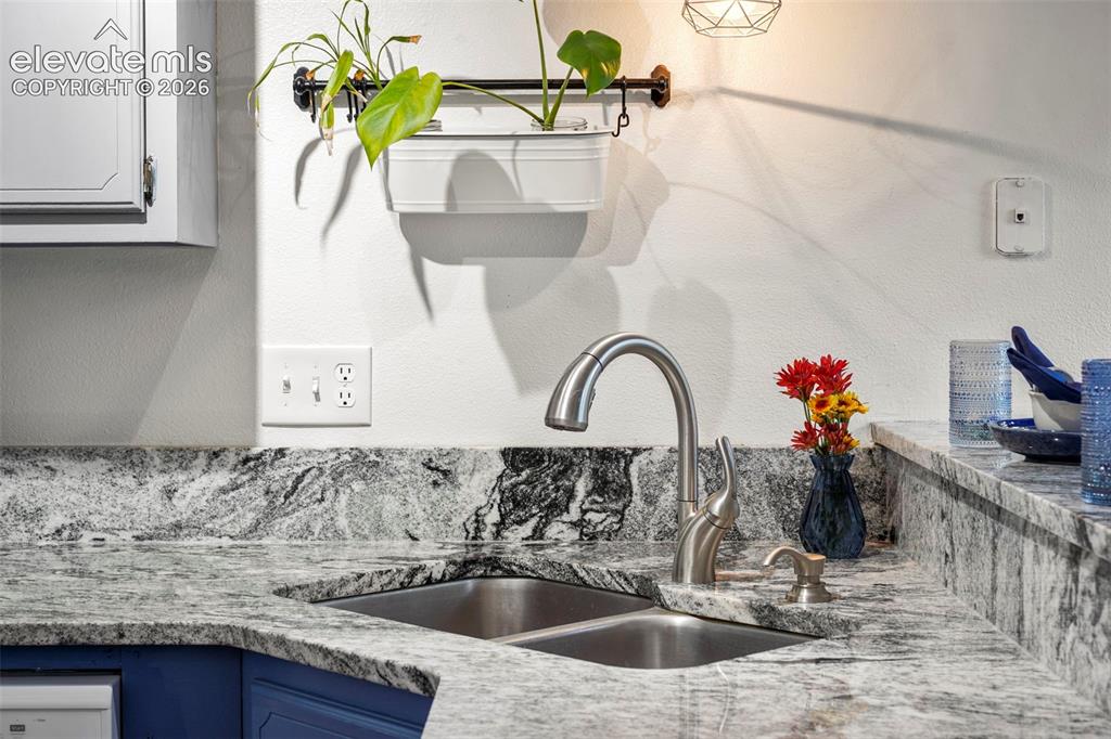 Image 14 of 28: Stone countertop with integrated matching backsplash, stainless steel doubl