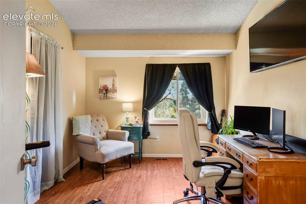 Image 17 of 28: Room featuring wood-finish flooring, textured ceiling, and a window with na