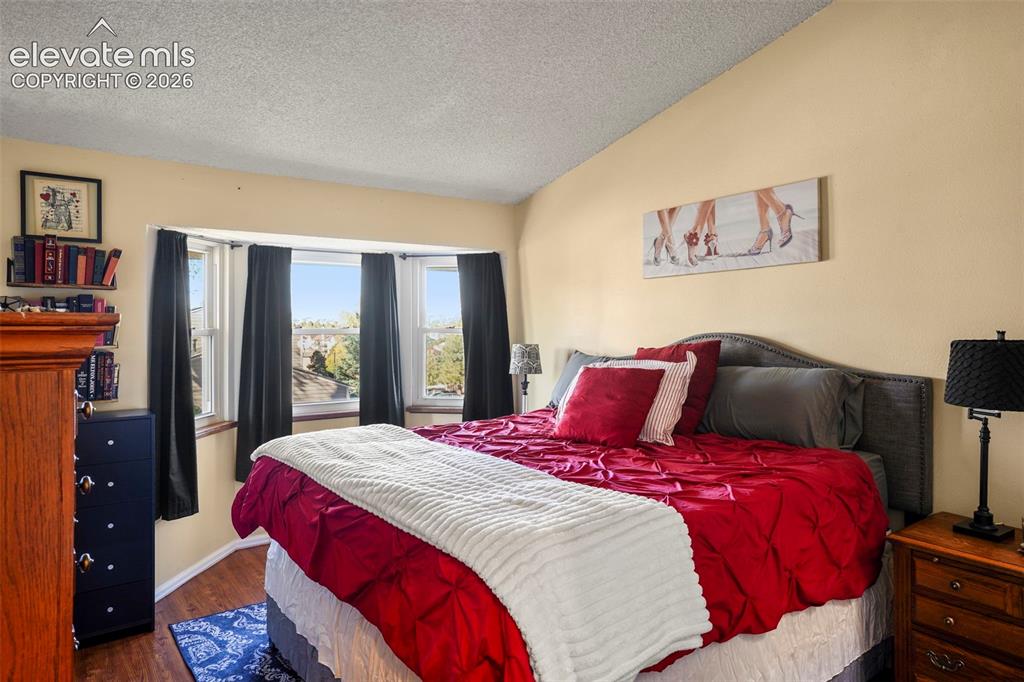 Image 20 of 28: Room featuring a vaulted ceiling, bay window, and wood-finish flooring