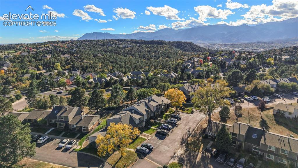 Image 25 of 28: Aerial perspective featuring multi-level residential structures, paved park