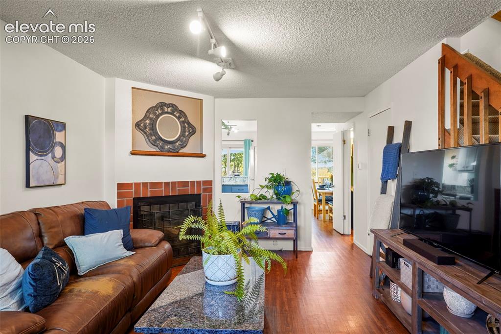 Image 5 of 28: Living area featuring wood-finish flooring, a brick fireplace surround, adj