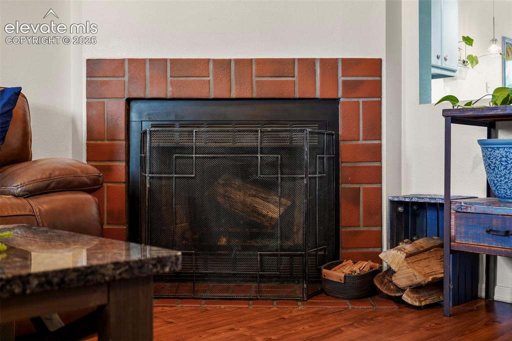 Image 6 of 28: Fireplace featuring a red brick surround, dark metal insert, and matching b