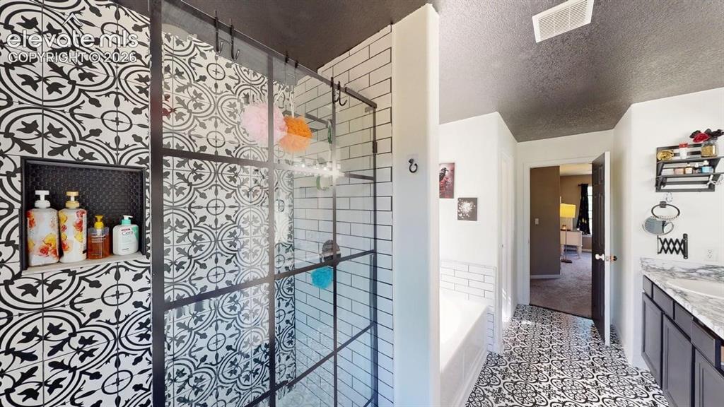 Image 14 of 22: Patterned floor tiling, glass-enclosed shower with black grid accents, subw