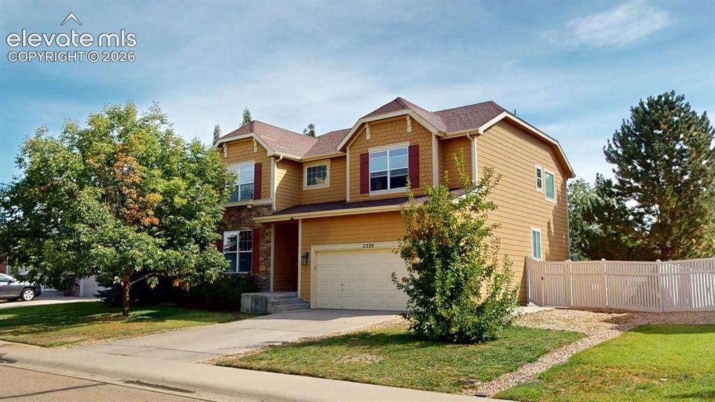 Image 2 of 22: Two-story residence featuring a two-car garage, stone accents, and a fenced