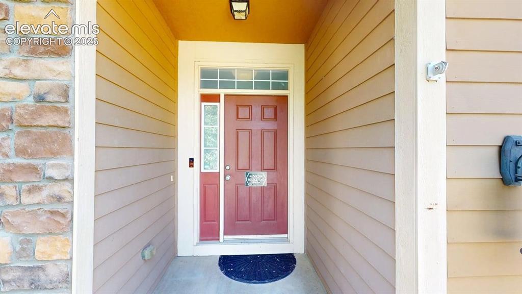 Image 4 of 22: Red paneled entry door with transom window and sidelight