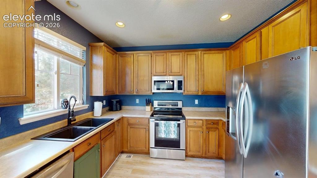 Image 5 of 22: Kitchen featuring wood-finish cabinetry, stainless steel appliances, a doub