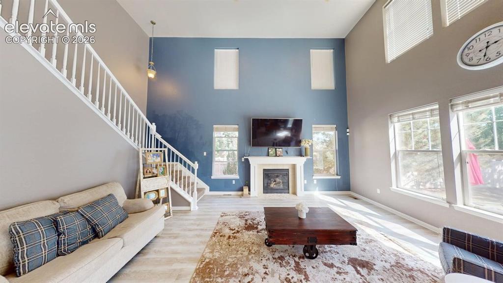 Image 7 of 22: Two-story living space featuring high ceilings, a white-mantled fireplace, 