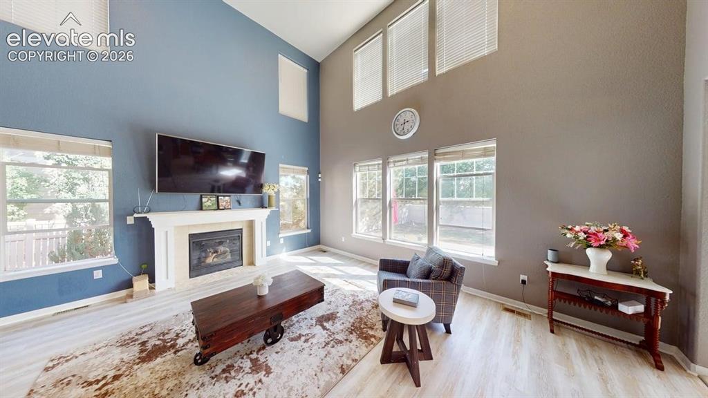 Image 8 of 22: Two-story living area featuring a fireplace with a white mantel, high ceili