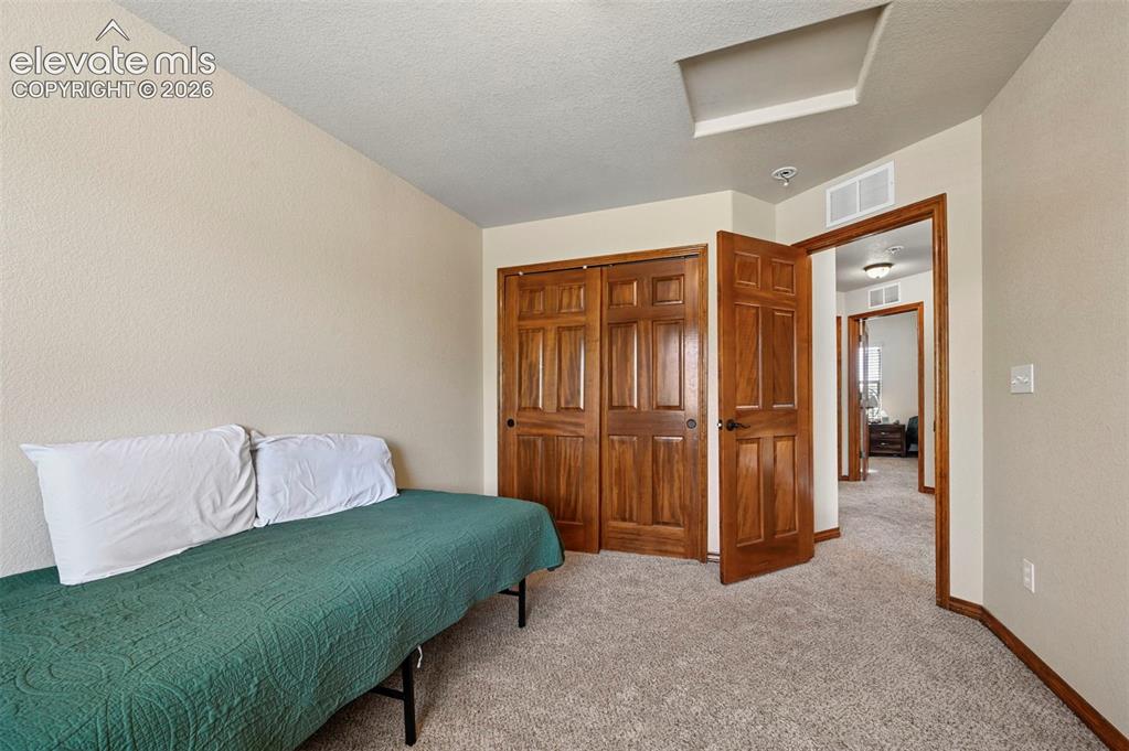 Image 12 of 34: Bedroom featuring neutral-toned walls, textured carpet flooring, and solid