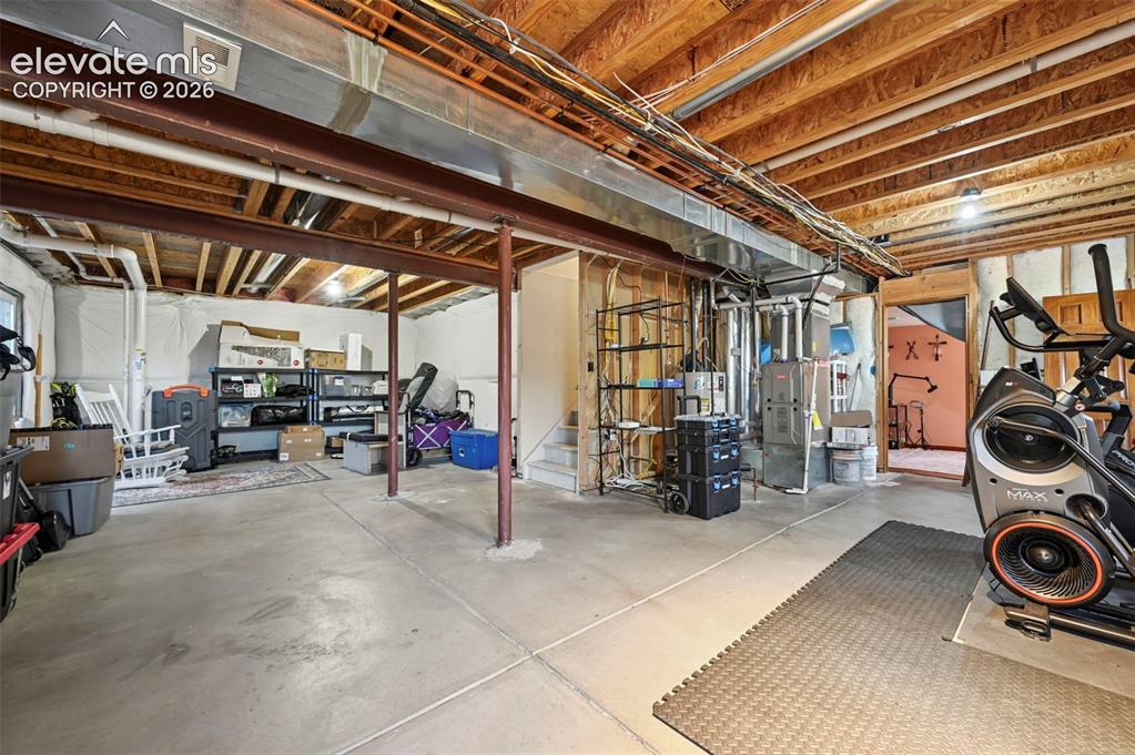 Image 16 of 34: Unfinished basement featuring exposed wood joists, concrete flooring, and a