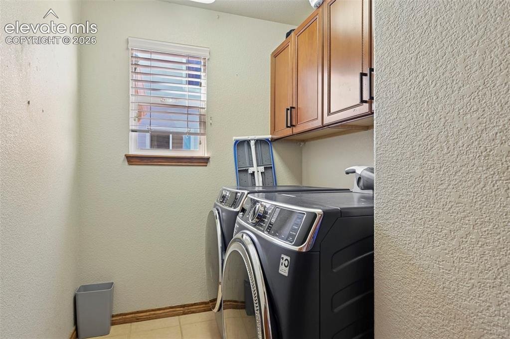 Image 18 of 34: Utility space with upper cabinetry featuring wood-finish doors and matte bl