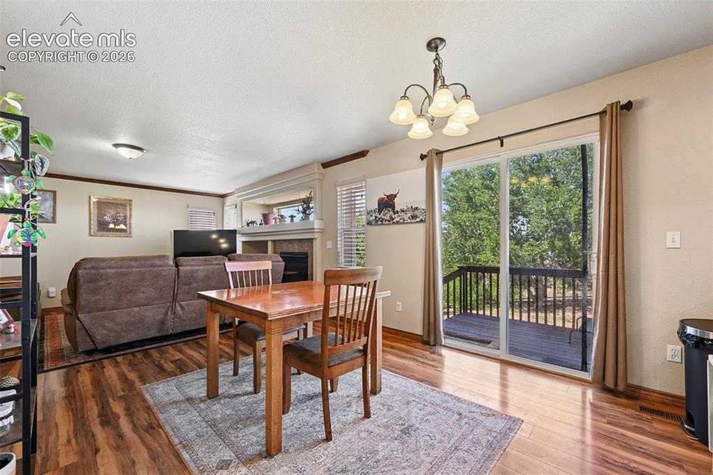 Image 21 of 34: Living area featuring wood-finish flooring, a fireplace with a stone surrou