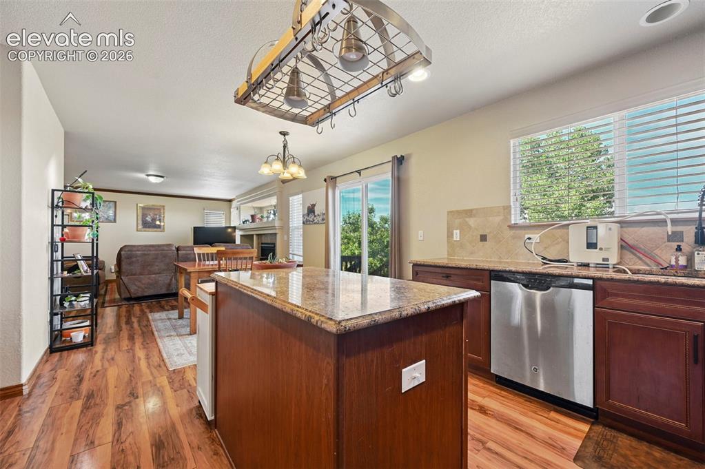 Image 22 of 34: Kitchen featuring wood-finish flooring, an island with a stone countertop,