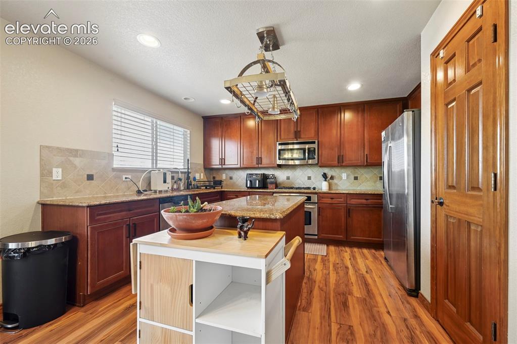 Image 24 of 34: Kitchen featuring wood-finish flooring, wood cabinetry, stainless steel app