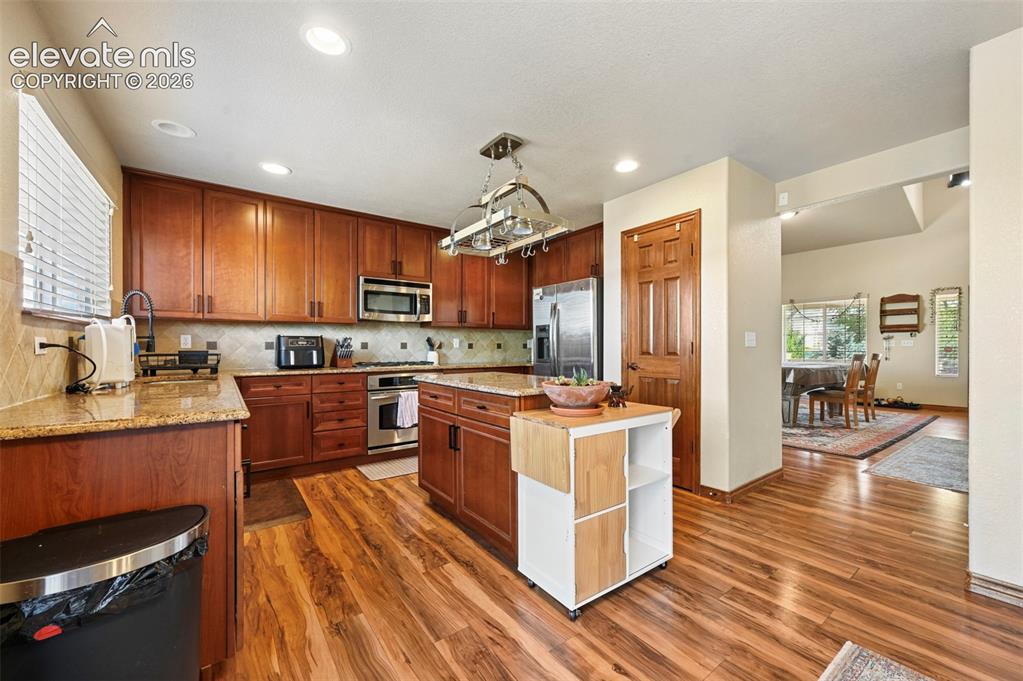 Image 4 of 34: Kitchen featuring wood-finish flooring, recessed lighting, and rich wood ca