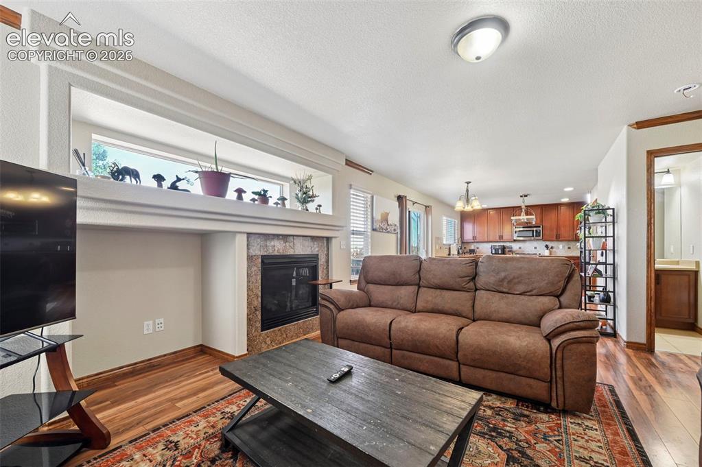 Image 5 of 34: Living area featuring a fireplace with a tiled surround, a decorative mante