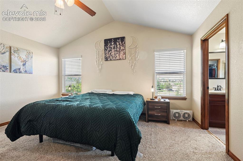 Image 6 of 34: Vaulted ceilings highlight this carpeted room featuring two windows with bl