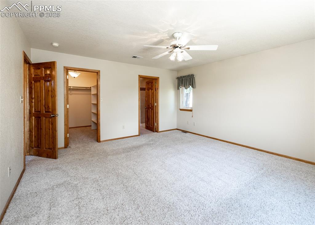 Image 25 of 48: Another view of the primary bedroom with walk-in closet and ensuite bath.