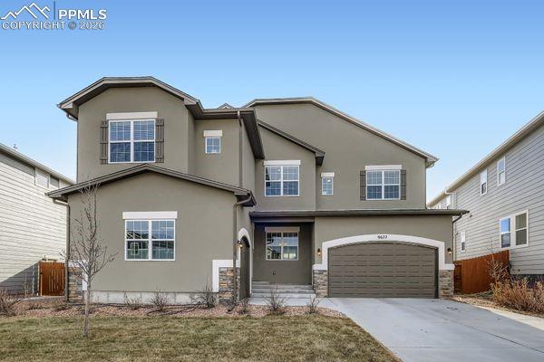 Caption: View of front facade with stucco siding, driveway, and an attached garage
