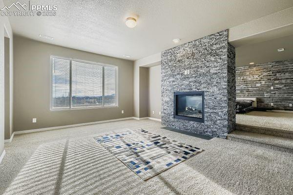 Image 20 of 35: Unfurnished living room with a fireplace, carpet, and a textured ceiling