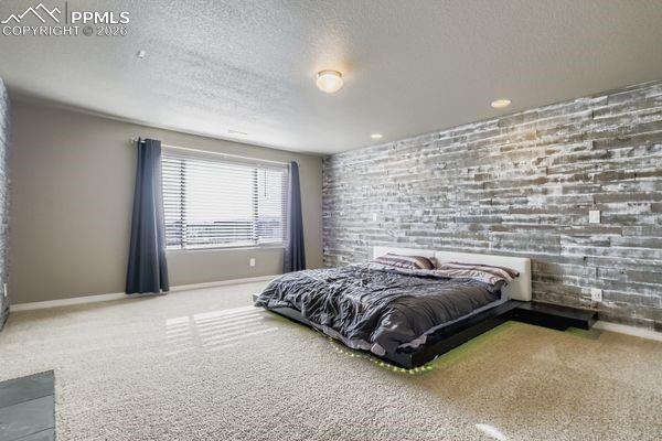 Image 22 of 35: Carpeted bedroom with a textured ceiling and an accent wall