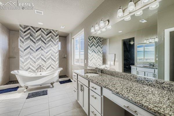 Image 23 of 35: Full bathroom with vanity, a soaking tub, and light tile patterned floors