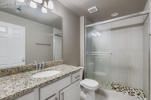 Image 31 of 35: Full bath featuring a shower stall, vanity, a textured wall, a textured cei