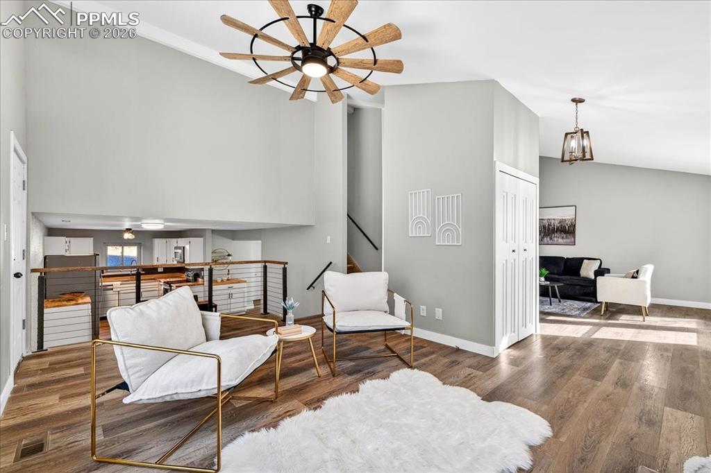 Image 10 of 49: Sitting room with a ceiling fan, wood finished floors, a high ceiling, and