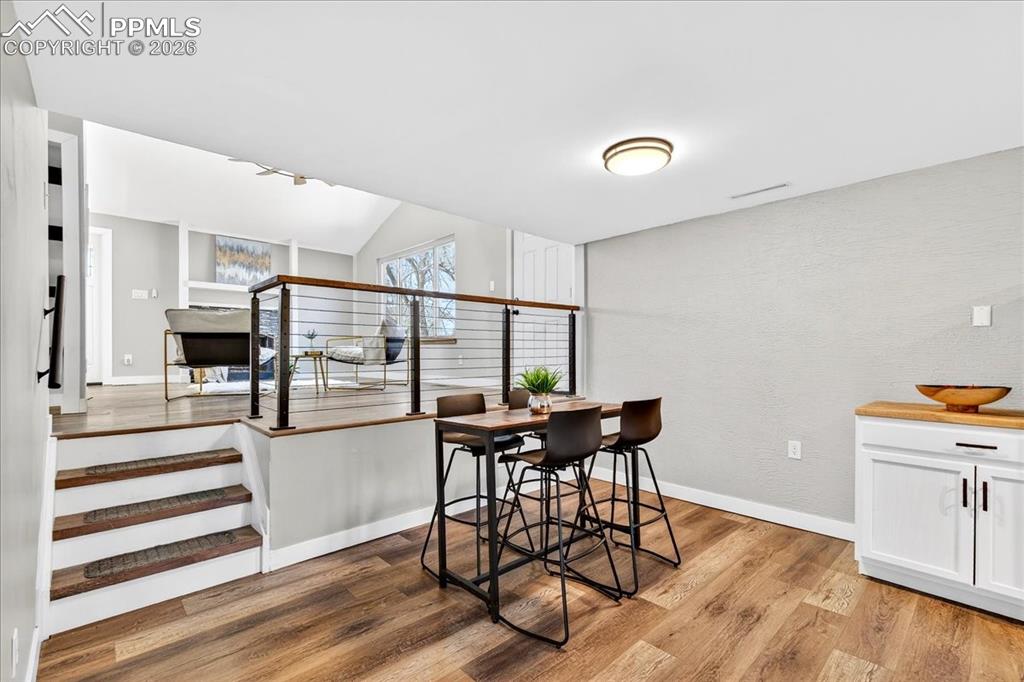 Image 15 of 49: Dining room with light wood-type flooring and vaulted ceiling
