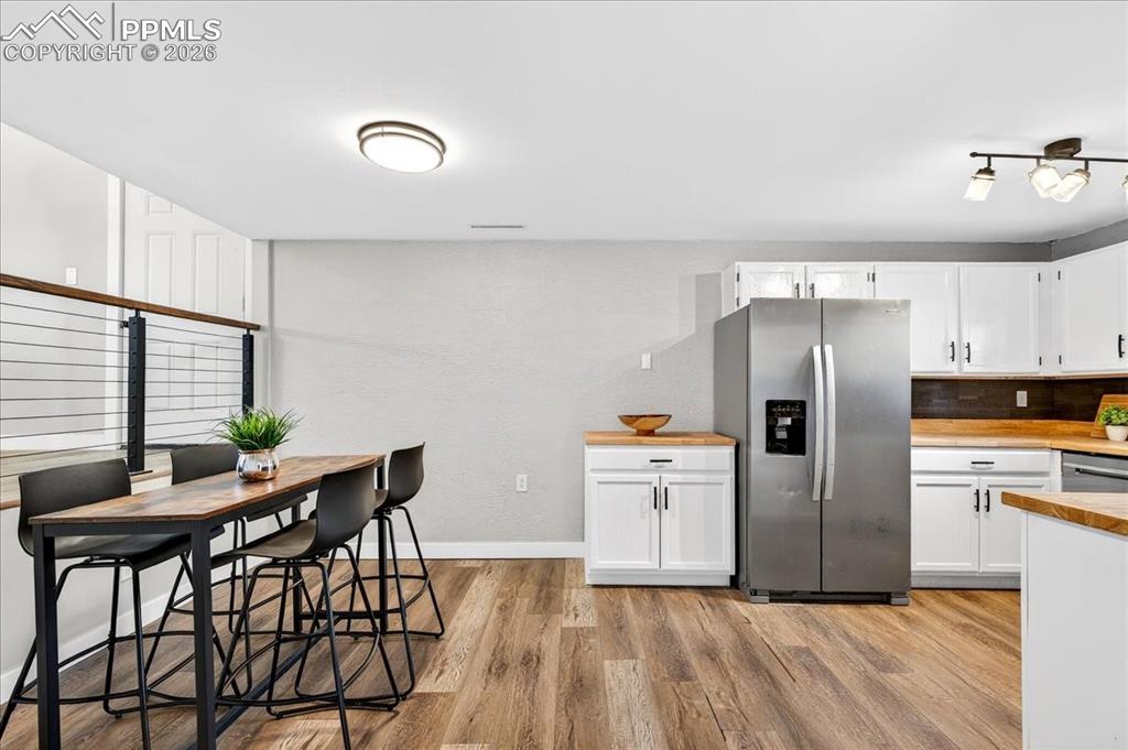 Image 16 of 49: Kitchen featuring stainless steel appliances, white cabinetry, light wood-s