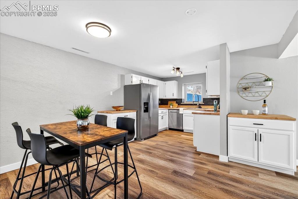 Image 18 of 49: Kitchen with stainless steel appliances, white cabinets, light wood-style f
